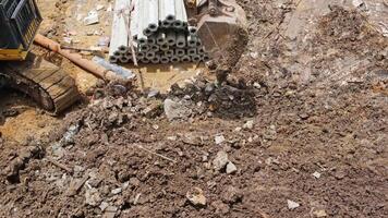 A large yellow excavator uses its bucket to level the ground in a construction area for buildings and homes removing debris and waste to ensure the site is kept clean video