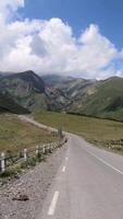 Vertical. Driving on the road in a mountain alley with a view of the mountain ranges and the sky video