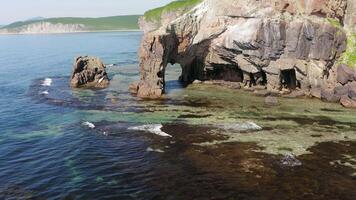 Drone view of a natural stone arch on the seashore on a sunny day video