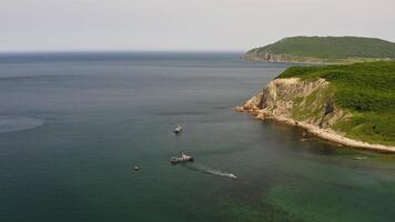 Drone view of a fishing schooner anchored near a beautiful rocky promontory video