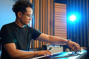 Musician playing music keyboard, Asian man in black shirt playing piano and practicing in home studio photo