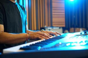 Close up of Musician playing music keyboard, Asian man in black shirt playing piano and practicing in home studio photo