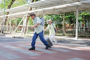 Asian senior couple traveler, Man and woman cross the road in downtown photo