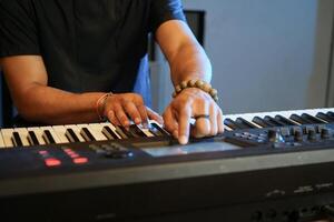 Musician playing music keyboard, Close up of Asian man hand in black shirt playing piano and practicing in home studio photo