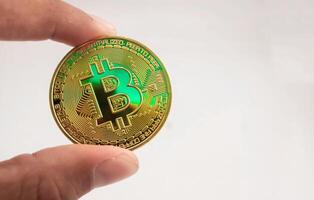 bitcoin on hand with isolated white background. bitcoin made from metal wth gold color. bitcoin is pupular cryptocurrency in world. bitcoin is a digital investment asset of the future. photo
