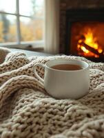 Hot cappuccino warming on cozy blanket near fireplace in autumn photo