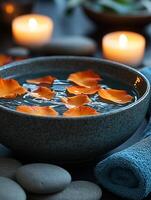 Rose petals floating in bowl creating relaxing spa ambiance with candles and stones photo