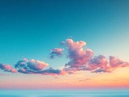 Pink clouds drifting across a sky at sunset over calm ocean photo