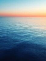 Calm ocean waves reflecting sunset colors during twilight photo