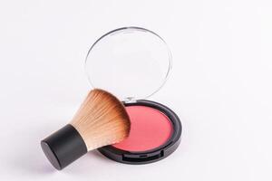 An open round pack of compact blush in a pink tone with a professional fluffy short makeup brush. isolated on a white background. A copy space. photo