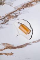A chic cosmetic bottle with serum for daily self-care on a white tray in the form of a shell. top vertical view. Abstract marble. Natural Cosmetic. photo