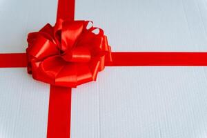 A white present adorned with a vibrant red ribbon and bow photo