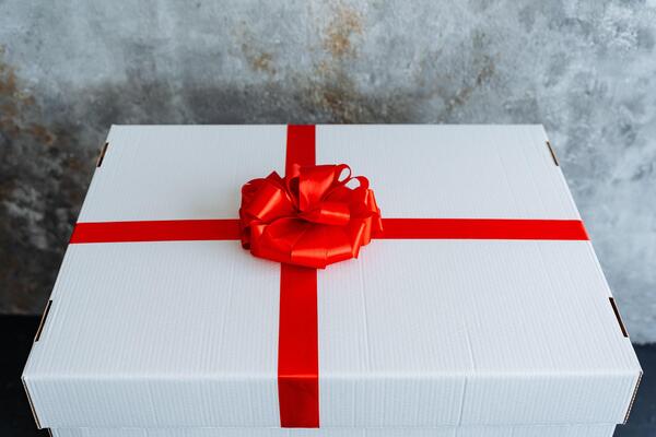 Rectangular white box adorned with a crimson ribbon and bow