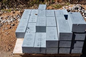 Raw concrete blocks neatly arranged on pallet, stacked outdoors at construction site. Essential building materials for foundations and walls in heavy infrastructure projects photo