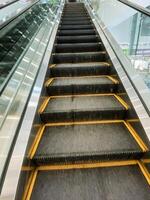 A wooden parallel rectangle building with a close-up yellow-lined escalator made of composite material, metal, glass, and track. photo