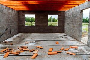 Currently, a garage is being constructed, featuring bricks scattered across the floor and a wooden ceiling overhead, contributing to the overall atmosphere of the building project photo