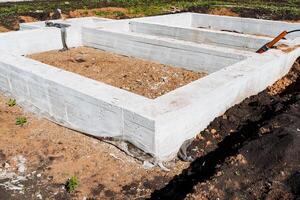 Construction of a new residential house under sunny skies, with the concrete foundation being laid on the construction site. The start of a solid base for the future development project photo