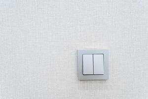 Rectangular white light switch on a white wall with symmetrical placement photo