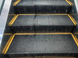 Closeup of a symmetrical escalator with yellow striped steps made of composite material photo