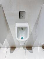 Plumbing fixture in public restroom with blue button is a product found in a bathroom, such as a toilet or urinal, made of wood and shaped in a rectangle on the flooring. photo