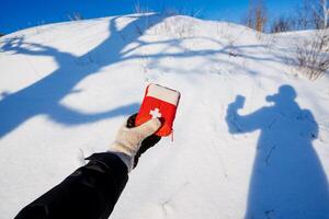 Hiker holding first aid kit in hand on background of his shadow in the snow, safety concept on hiking, mountain adventure alone photo