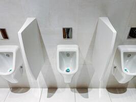 A row of urinals in a public restroom with dividers between them photo