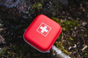 Red first aid kit on mossy forest floor essential gear for outdoor safety and adventure. Portable, bright, and protective with medical supplies for wilderness emergencies photo