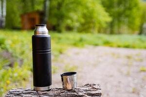 Stainless steel thermos flask for outdoor adventures in the forest. Ecofriendly, sustainable, and reusable. Keeps beverages hot or cold. Perfect for camping, hiking, and picnics photo