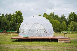 Experience a geodesic dome tent on a wooden platform in a tranquil natural setting, perfect for a serene and sustainable ecofriendly retreat amid verdant surroundings photo