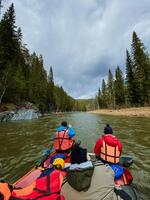 A lively group of people is enjoying their time together in a bright red canoe as they paddle down a peaceful river, surrounded by nature and taking in the beautiful scenery around them photo