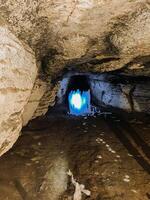 There is a cave that has a bright light shining out from within it, making it an intriguing and mysterious sight to behold, likely due to its unique geological features and formations photo