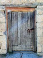 There is a beautifully crafted wooden door set into a sturdy stone wall, and it features a key resting on its surface, suggesting a sense of mystery and potential security photo