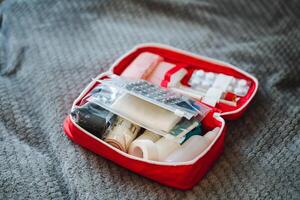 A bright red first aid kit placed on a neatly made bed indicates that this household is exceptionally wellprepared for any unexpected medical emergencies that may arise at any time photo