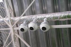 In the interior space of the building, there are three security cameras that are strategically hanging from the ceiling to monitor the area effectively and ensure security photo
