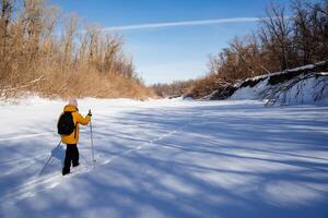 Man with backpack on his back skiing in winter forest, woman traveling alone in snow, exploring new terrain. photo