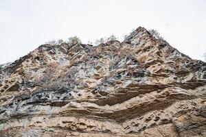 The image features a closeup view of a rocky mountain portrayed against a clean, white background that contrasts beautifully with the intricate details of the rock formation photo