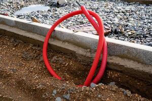 A vibrant red pipe is casually laying on the dirtcovered ground, blending in with the natural surroundings, creating an interesting visual contrast against the earthy tones and textures photo