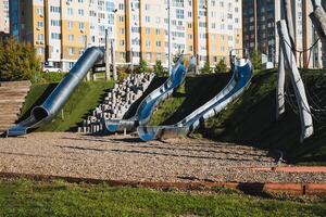 A vibrant playground featuring a colorful slide and sturdy stairs, conveniently located in front of a tall building, providing a fun and enjoyable space for children to play photo