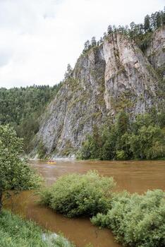 A serene river winds its way through a dense forest, with a grand rocky structure in the distance, creating a peaceful and unspoiled natural scene that is filled with tranquility and beauty photo