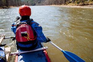 An adventurous kayaker embarks on a thrilling journey, skillfully navigating a serene and beautiful river during the enchanting springtime season photo