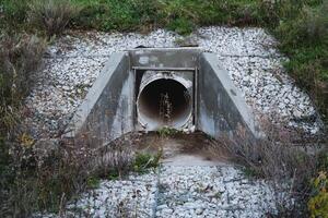 A large pipe is emerging from a concrete structure, protruding prominently and likely serving a significant function in the overall design and utility of the surrounding area photo