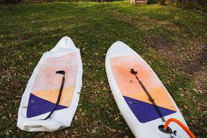 Two SUP boards are lying on the grass, the process of pumping air into a board with a paddle. photo