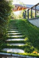 There exists a stunningly beautiful set of stairs that ascends up to a delightful house, which is encompassed by an abundance of lush green grass, making for an inviting and warm atmosphere photo
