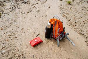 Carmine backpack by toy first aid kit on sand, not waste photo