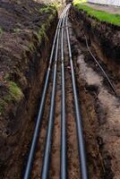 A collection of black pipes can be seen resting on the dirt surface, creating a striking contrast against the earth, and hinting at potential construction or maintenance work nearby photo