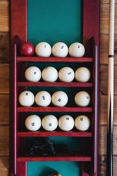 An elegant pool table showcases colorful billiard balls neatly arranged on its shiny surface, with a cue stick beside them, ready for an exciting game of skill and strategy photo