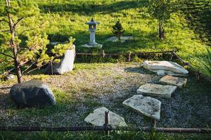 In the center of the garden, there stands a beautiful lantern, illuminating the area with its soft glow and enhancing the overall ambiance of the natural landscape that surrounds it photo