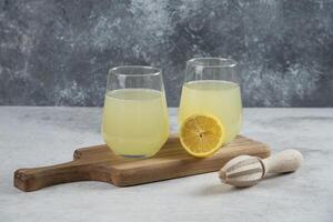 two glasses of lemonade with a wooden cutting board photo
