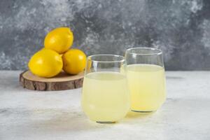 Two glass cups of lemonade with lemons photo