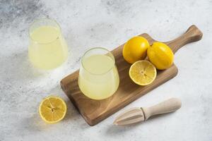 Two glass cups of lemonade and wooden reamer photo